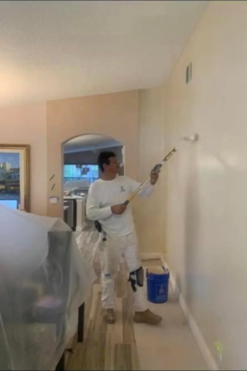 Painter rolling a bedroom wall during a whole-house repaint