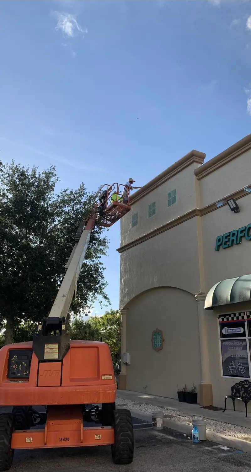 Eagle Painting boom lift on the facade of a commercial plaza in Broward County